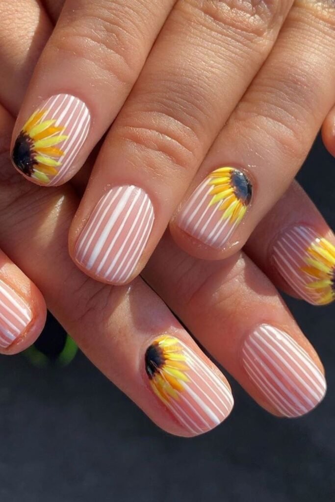 If you’re into simple sunflower nails, this set keeps it fresh while still making a bold statement. The mix of crisp white vertical lines on a soft pink base paired with delicate sunflower nails near the cuticle makes this look modern and playful. Perfect if you’re looking into a short sunflower nail designs.