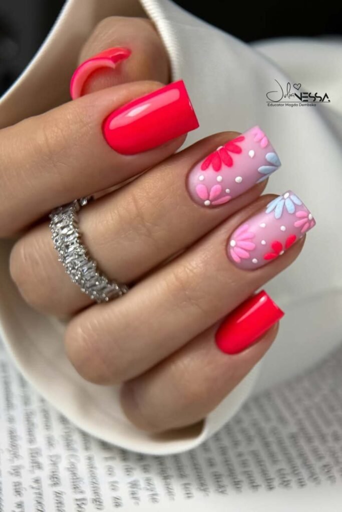 Neon red nails with delicate floral art.