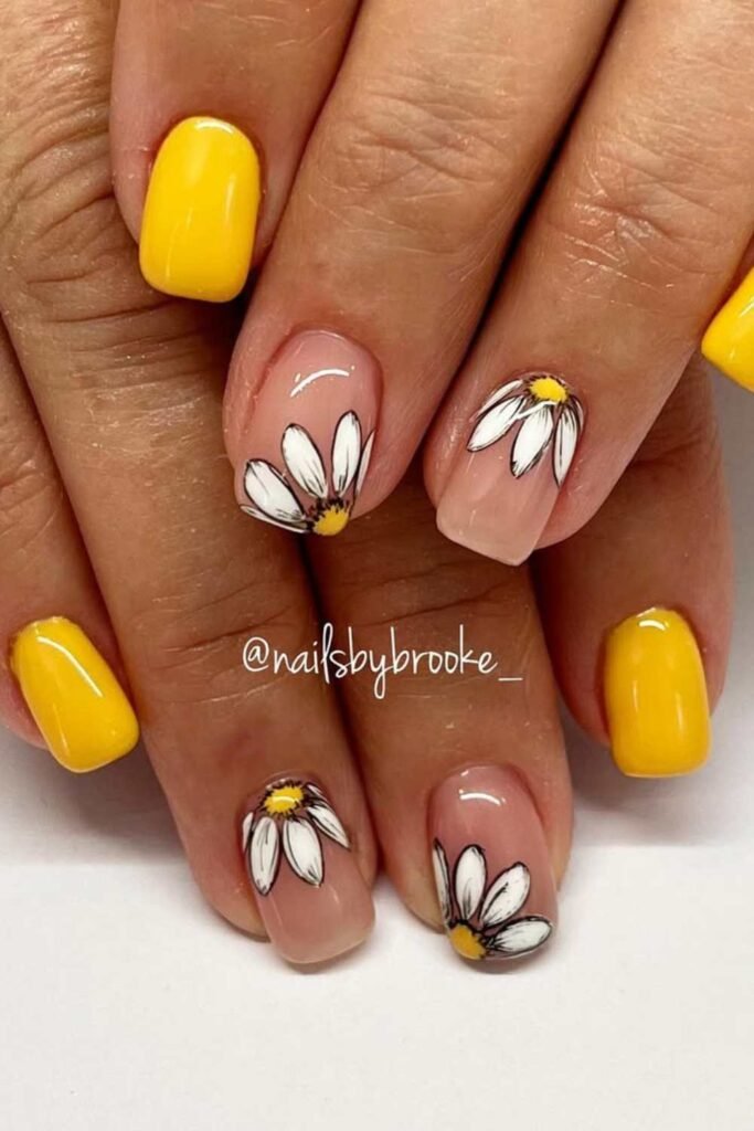 Yellow and nude nails with floral accents.