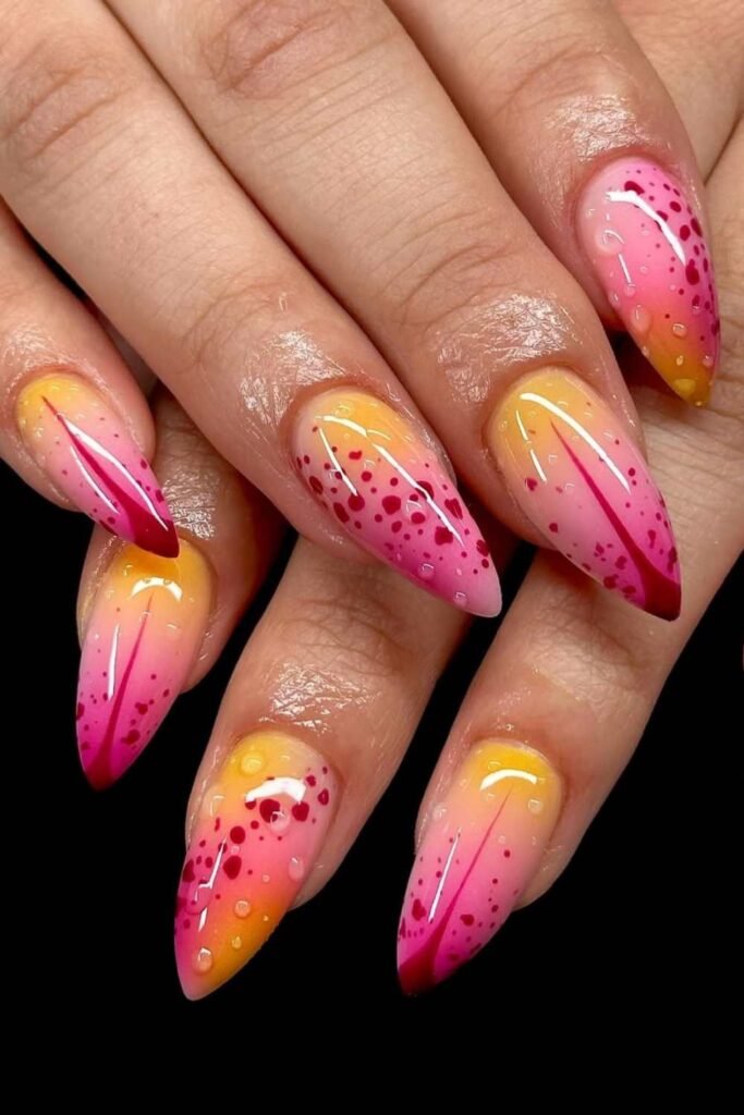 Almond-shaped nails with an ombre blend of pink, coral, and yellow, accented by petal-like details and dewy dot effects—perfect for a bold spring break manicure.