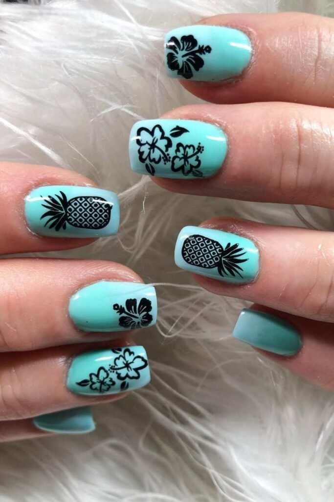 Teal nails with black daisy and pineapple designs.